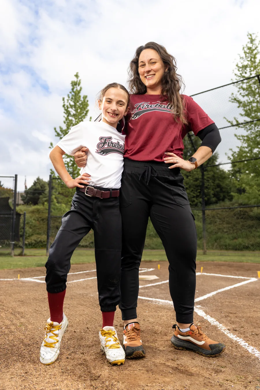 Assistant coach Kim Bertsch with her daughter at home plate, both in Fireballs gear.